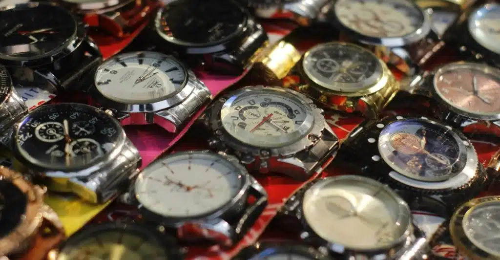 A close-up overhead view of numerous watches with various styles and colors, packed closely together on a surface.