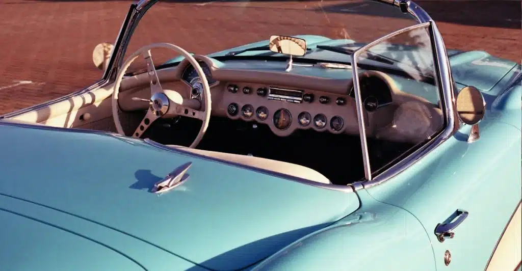 The interior and front hood of a light blue vintage convertible car with a tan dashboard.