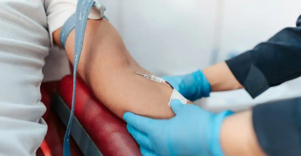 A close-up of a person's arm as a healthcare professional draws blood with a needle.