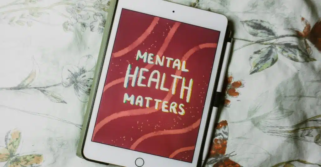 A tablet displaying "MENTAL HEALTH MATTERS" resting on a journal.
