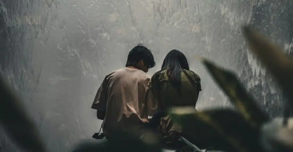 A man and a woman sitting with their backs to the camera, looking at a large indoor waterfall.