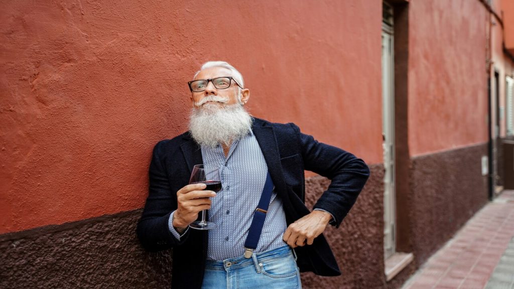 An old man with a mustache holding a glass of wine