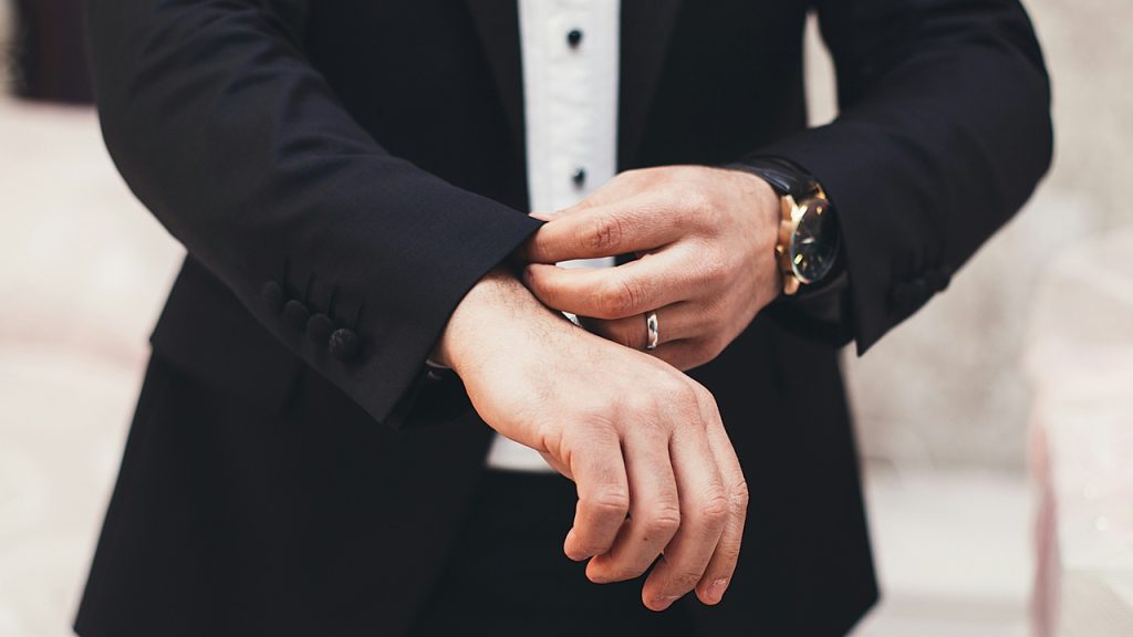 A man adjusting his suit’s sleeves.