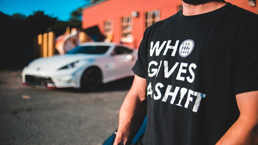 A man wearing a statement shirt with a white car in the background.
