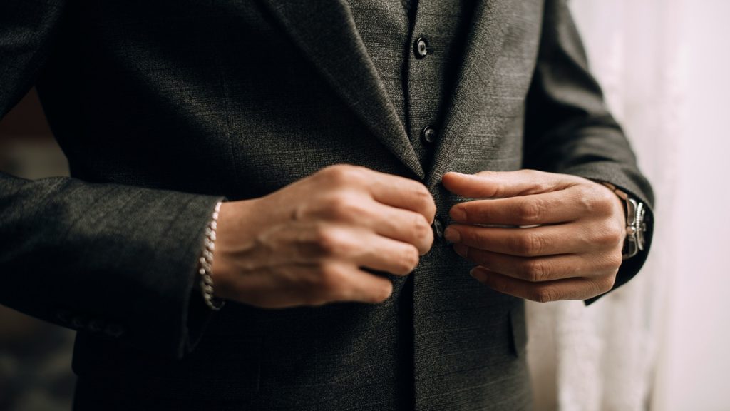A man fastening his suit jacket’s button.