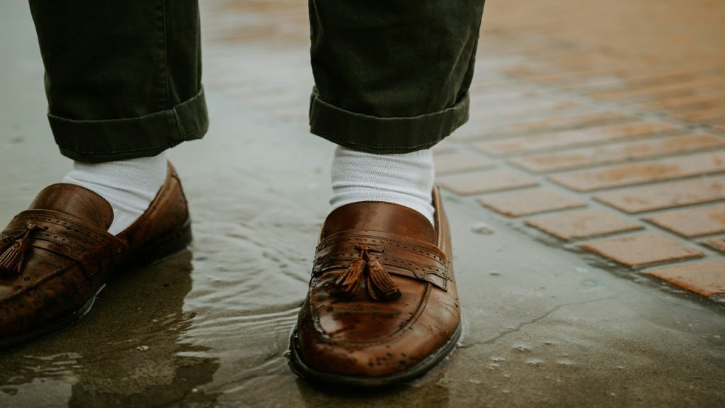 A person wearing brown dress shoes with white socks.