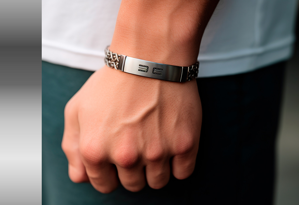 Close-up of a man's wrist wearing a silver chain bracelet engraved with letters