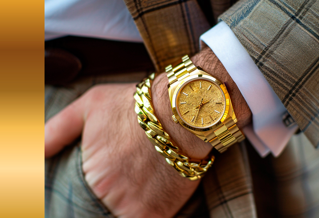 Close-up of a man's wrist wearing a gold watch and bracelet with a plaid suit