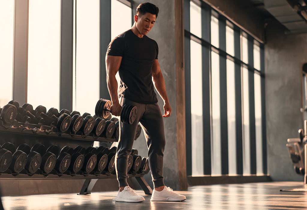 Man lifting dumbbell in sunlit gym