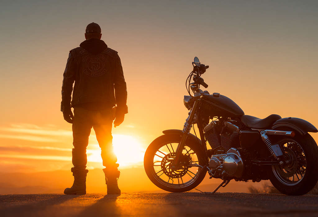 Biker silhouetted with motorcycle at sunset horizon
