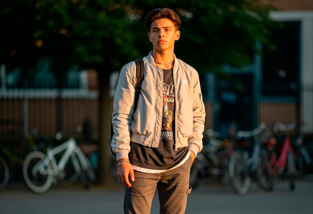 Teen boy in bomber jacket, graphic tee, cargo pants.
